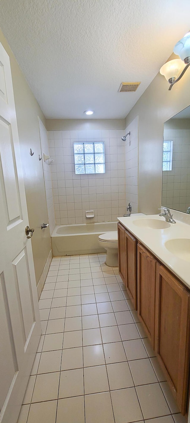 full bathroom featuring vanity, tiled shower / bath, tile patterned flooring, toilet, and a textured ceiling