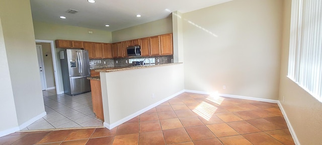 kitchen featuring sink, light tile patterned floors, appliances with stainless steel finishes, tasteful backsplash, and kitchen peninsula