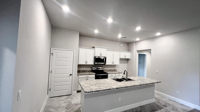 kitchen featuring light stone countertops, white cabinetry, sink, stainless steel appliances, and a center island with sink