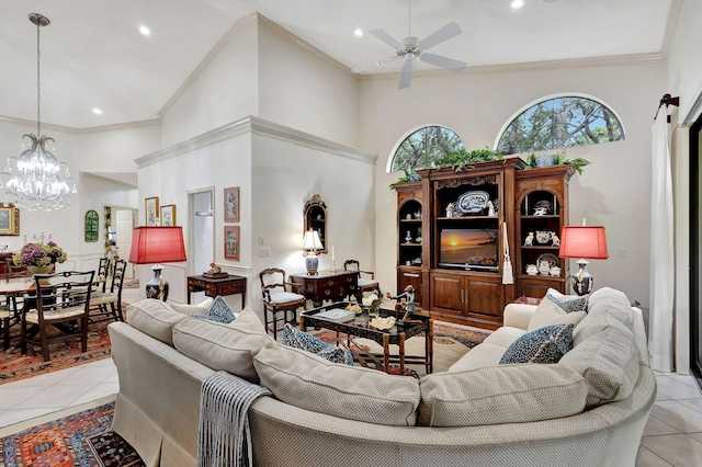 living room with ceiling fan with notable chandelier, a towering ceiling, ornamental molding, and light tile patterned floors