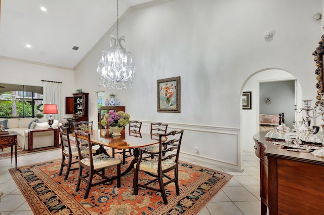 tiled dining area featuring a chandelier, ornamental molding, and high vaulted ceiling