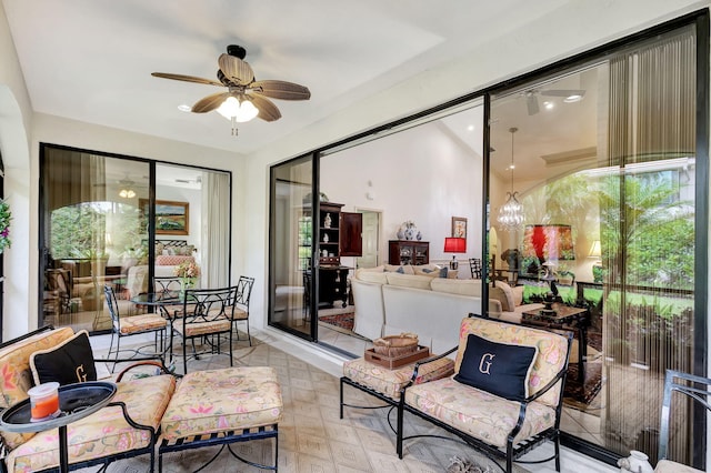 sunroom / solarium featuring ceiling fan with notable chandelier