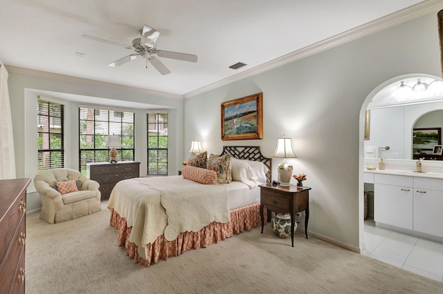 bedroom featuring ceiling fan, light tile patterned flooring, ensuite bath, and crown molding