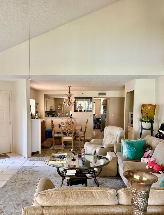 tiled living room with a notable chandelier, vaulted ceiling, and a textured ceiling