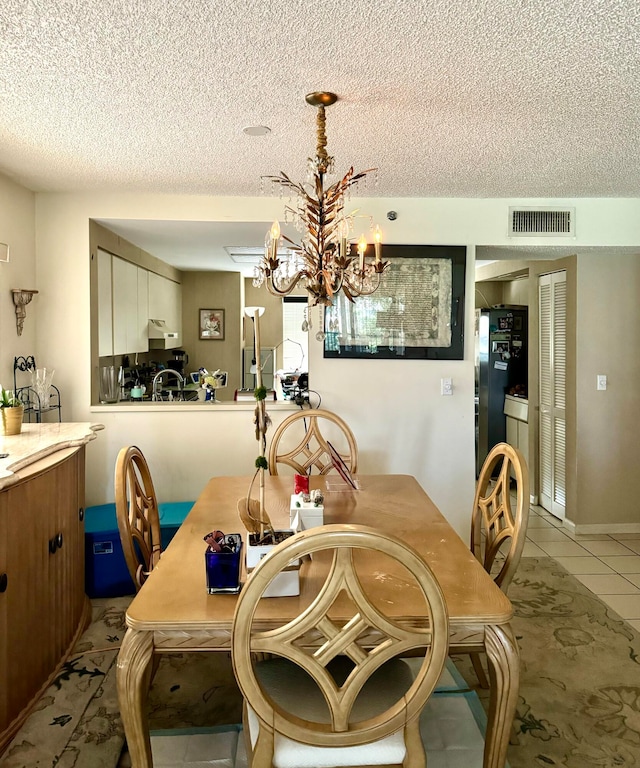 dining room with light tile patterned floors, a textured ceiling, visible vents, and an inviting chandelier