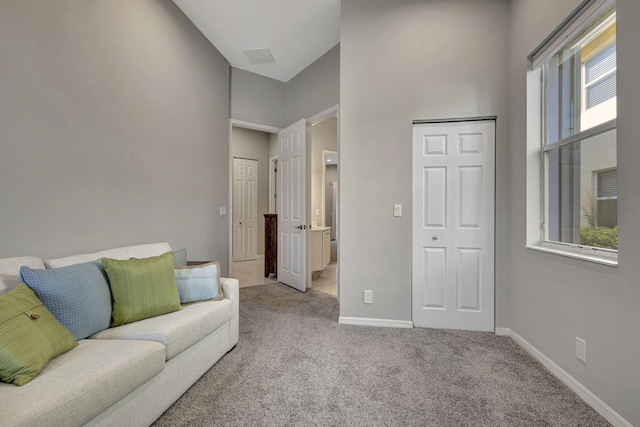 carpeted living room featuring a wealth of natural light and a towering ceiling