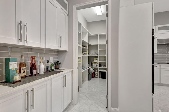 bar featuring tasteful backsplash and white cabinets