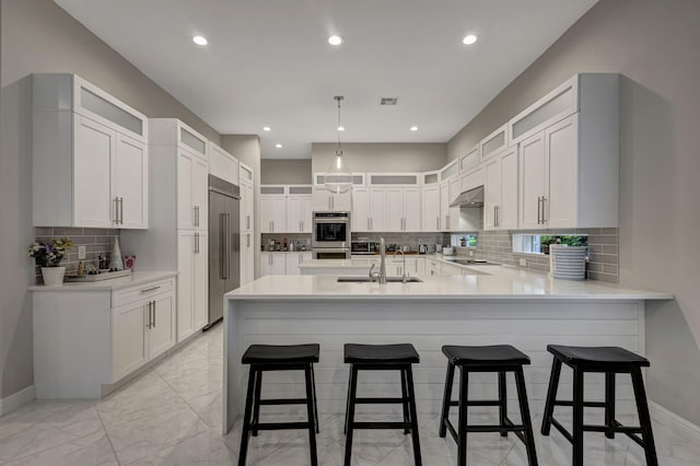 kitchen with kitchen peninsula, sink, decorative backsplash, a breakfast bar, and appliances with stainless steel finishes