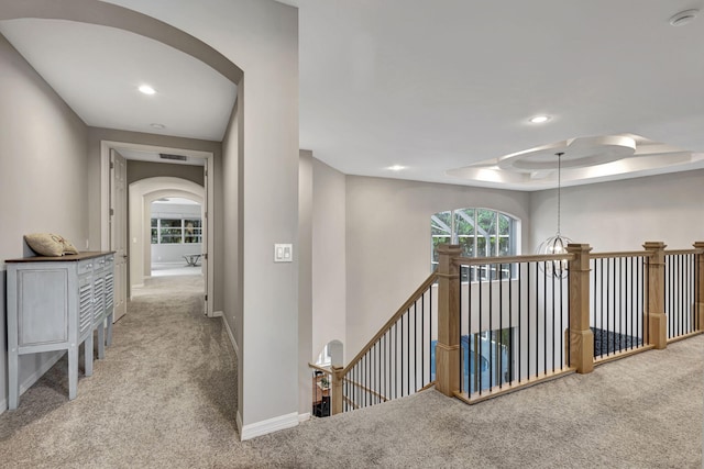 hall with a tray ceiling and carpet