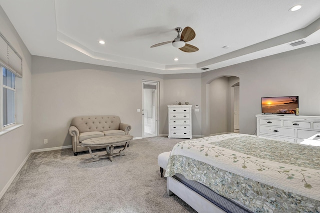 bedroom featuring light colored carpet, ceiling fan, and a tray ceiling