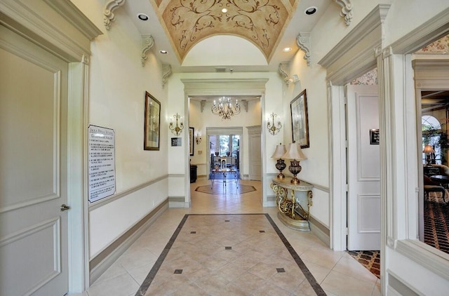 hall with ornamental molding, vaulted ceiling, a chandelier, and light tile patterned floors