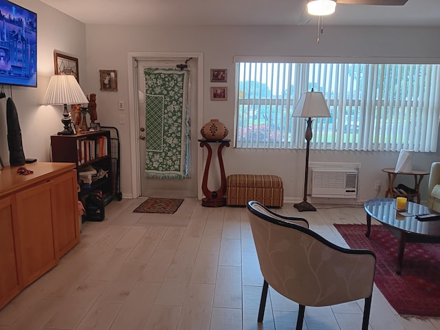 sitting room with a wall unit AC and ceiling fan