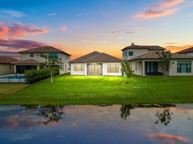 back house at dusk featuring a yard