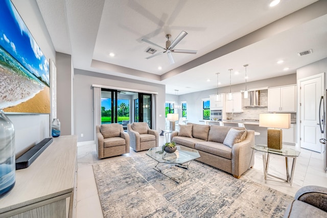 living room with ceiling fan and a raised ceiling