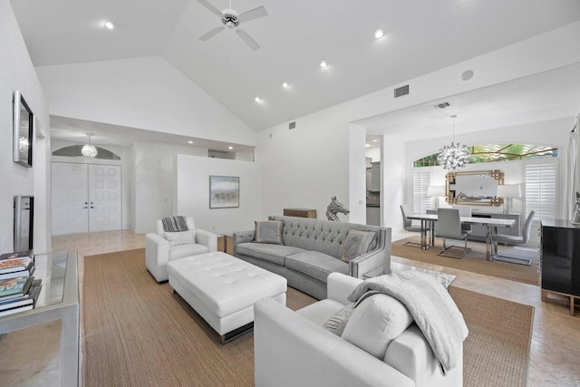 living room with ceiling fan with notable chandelier and high vaulted ceiling