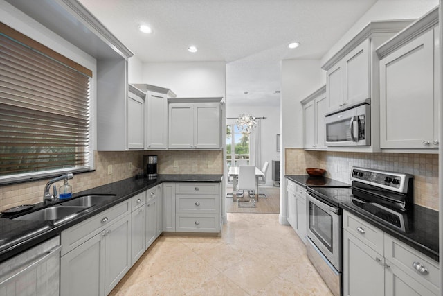 kitchen with a notable chandelier, tasteful backsplash, a textured ceiling, sink, and appliances with stainless steel finishes