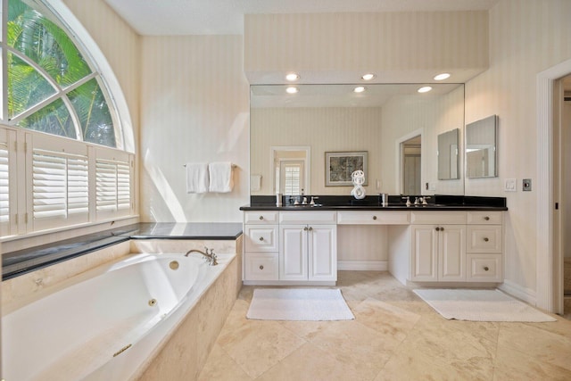 bathroom with tiled tub, vanity, and plenty of natural light