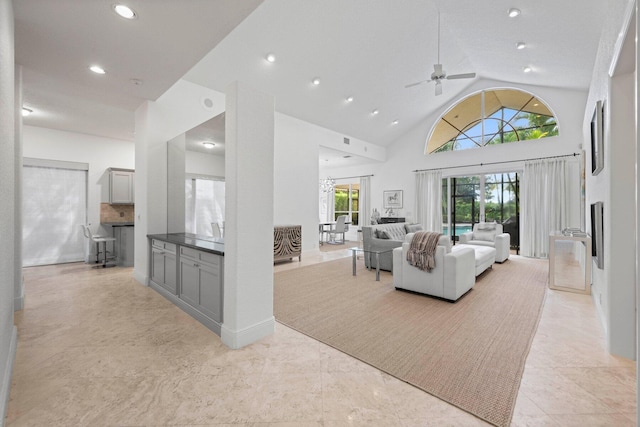 living room with ceiling fan with notable chandelier and high vaulted ceiling