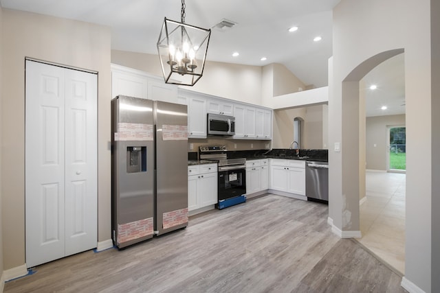 kitchen with light hardwood / wood-style floors, white cabinets, sink, pendant lighting, and appliances with stainless steel finishes