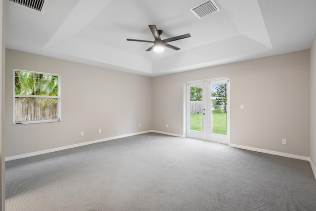 carpeted spare room featuring french doors, ceiling fan, and a raised ceiling