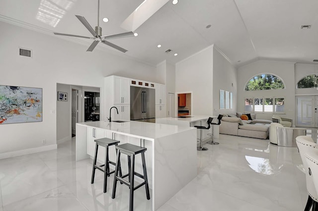 kitchen with white cabinetry, stainless steel built in fridge, a kitchen breakfast bar, light stone counters, and ceiling fan