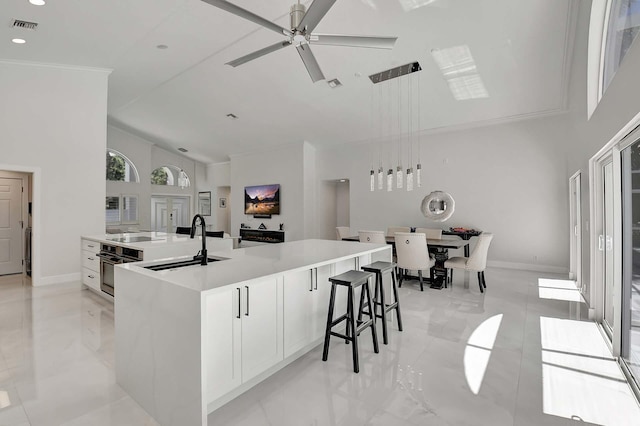 kitchen featuring white cabinets, ceiling fan, a large island, and sink