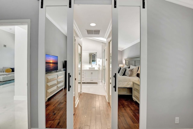 hall featuring a barn door, lofted ceiling, hardwood / wood-style flooring, and crown molding