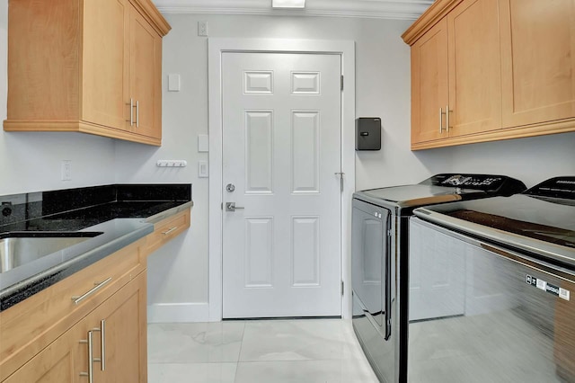 laundry area featuring crown molding, cabinets, washing machine and clothes dryer, and sink