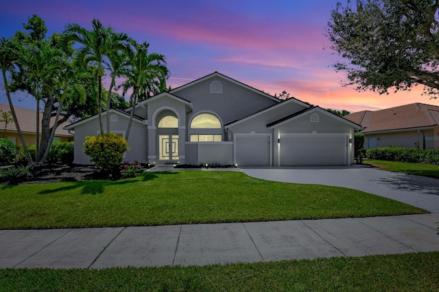 view of front of house featuring a garage, french doors, and a lawn