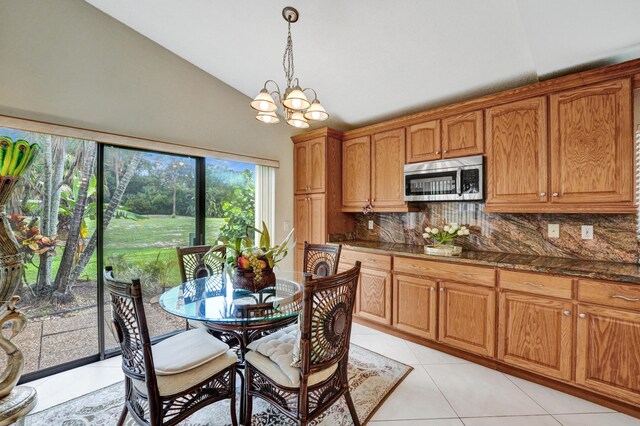 kitchen with pendant lighting, light tile patterned flooring, tasteful backsplash, vaulted ceiling, and an inviting chandelier