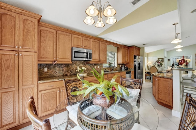 kitchen with hanging light fixtures, light tile patterned flooring, vaulted ceiling, stainless steel appliances, and an inviting chandelier