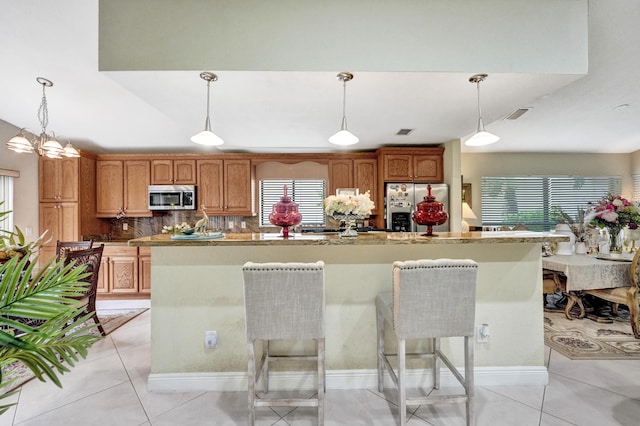 kitchen with pendant lighting, stainless steel appliances, light tile patterned floors, and a healthy amount of sunlight