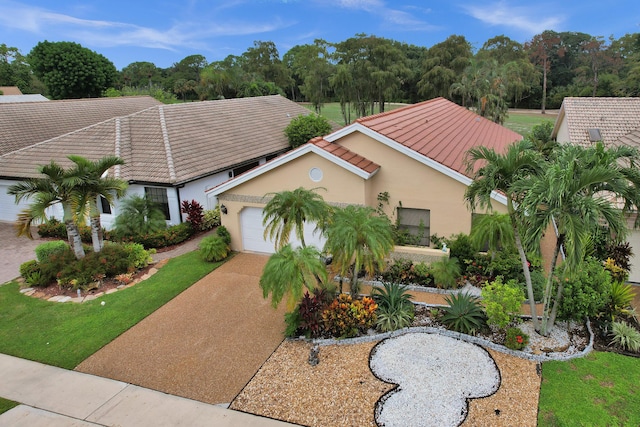 view of front of home featuring a tiled roof, an attached garage, driveway, and stucco siding