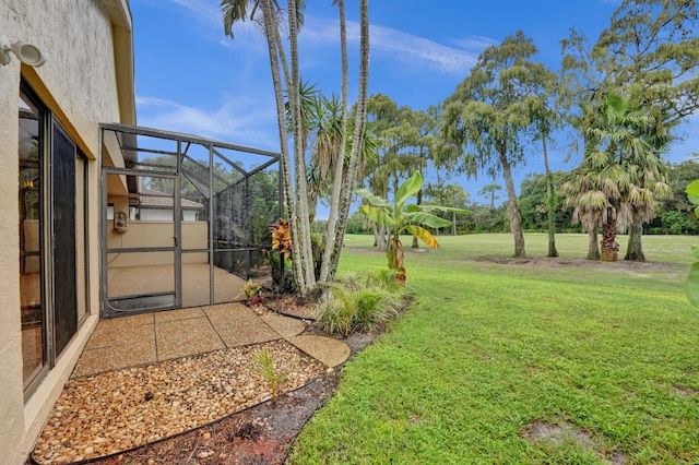 view of yard with glass enclosure and a patio area