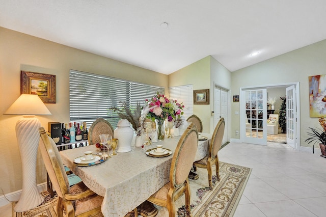 tiled dining space featuring lofted ceiling and french doors