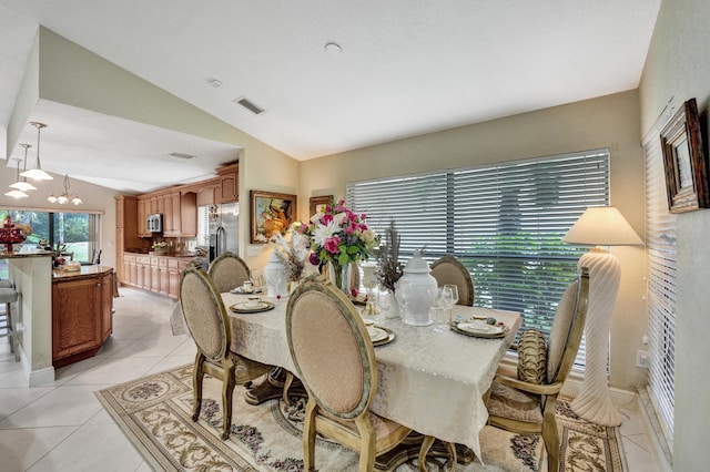 dining room featuring lofted ceiling, an inviting chandelier, and light tile patterned floors