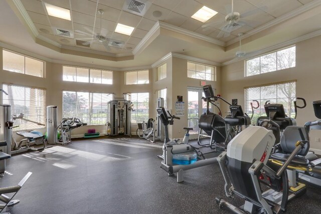 exercise room with ceiling fan, ornamental molding, a wealth of natural light, and a tray ceiling