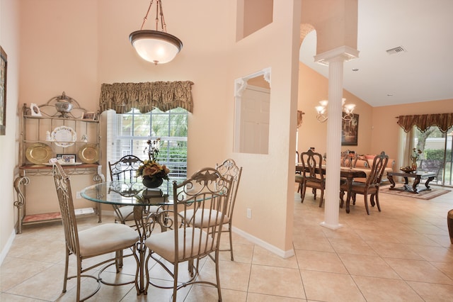 tiled dining space featuring a notable chandelier, high vaulted ceiling, and decorative columns