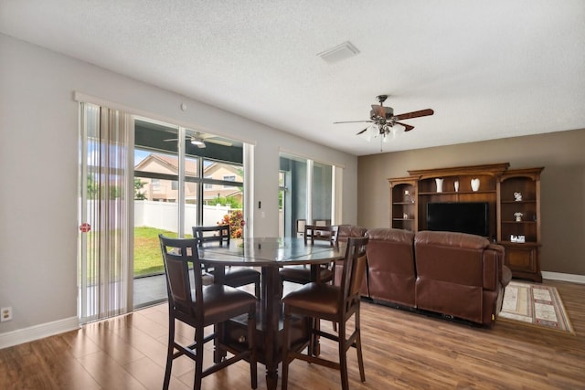 dining space with a textured ceiling, ceiling fan, and hardwood / wood-style flooring