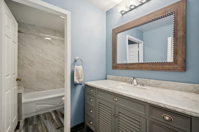 full bathroom featuring tiled shower / bath, vanity, toilet, and wood-type flooring