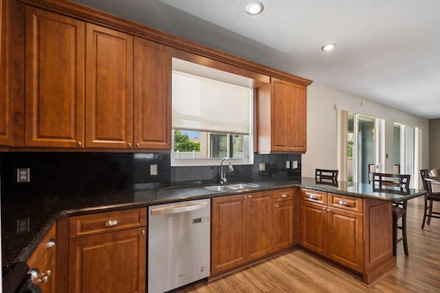 kitchen with dishwasher, light hardwood / wood-style floors, sink, kitchen peninsula, and decorative backsplash