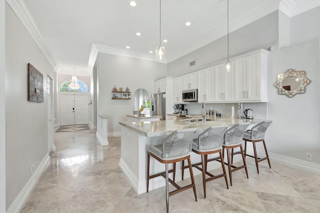 kitchen featuring appliances with stainless steel finishes, kitchen peninsula, white cabinets, and a breakfast bar