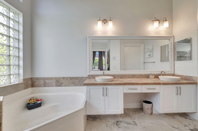 full bathroom with a garden tub, plenty of natural light, and a sink