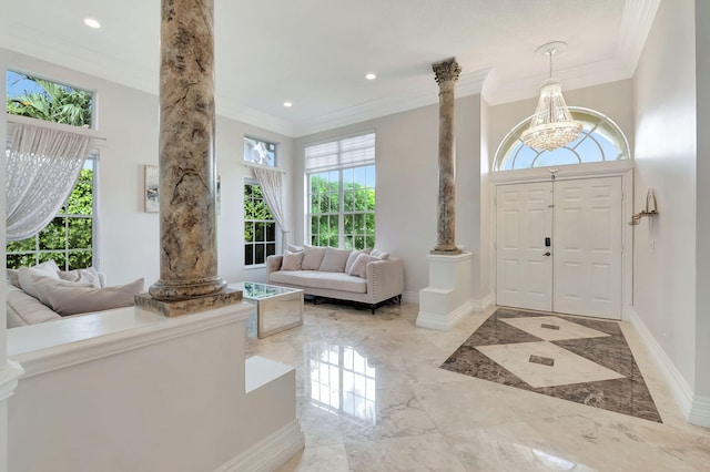 foyer featuring ornamental molding, a chandelier, and ornate columns