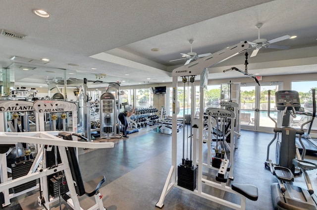 exercise room featuring a tray ceiling, recessed lighting, visible vents, a ceiling fan, and a textured ceiling