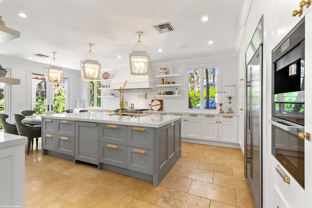 kitchen with pendant lighting, a wealth of natural light, and a center island with sink