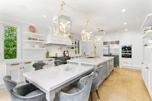 kitchen featuring an island with sink, high end appliances, a breakfast bar, and decorative light fixtures