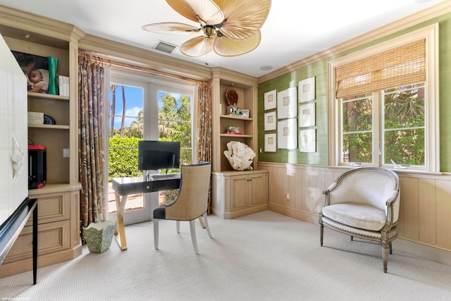 carpeted office with built in features, crown molding, ceiling fan, and wooden walls