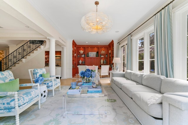 living room with ornamental molding, a notable chandelier, and ornate columns