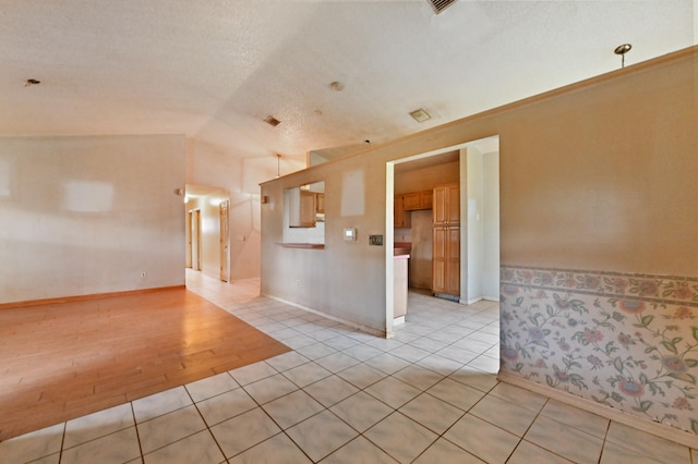 spare room featuring lofted ceiling, light hardwood / wood-style flooring, and a textured ceiling